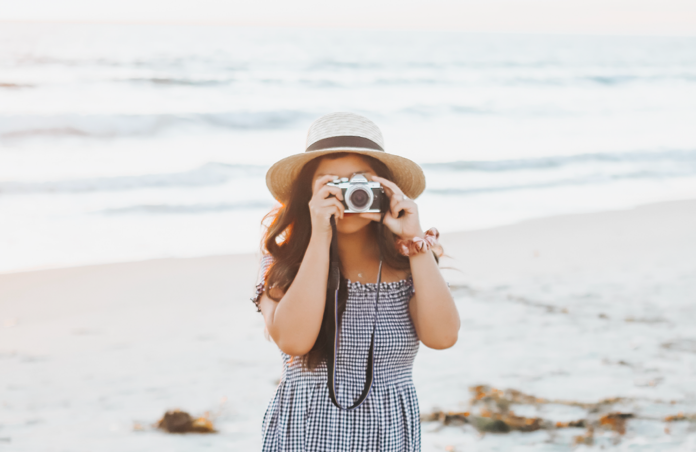 woman on beach holding vintage camera taking picture