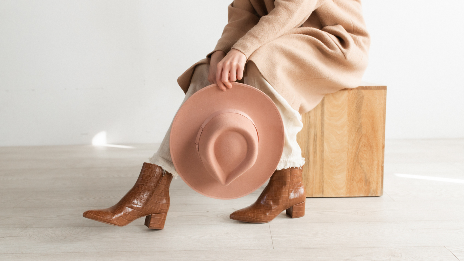 woman sitting holding a felt fedora hat