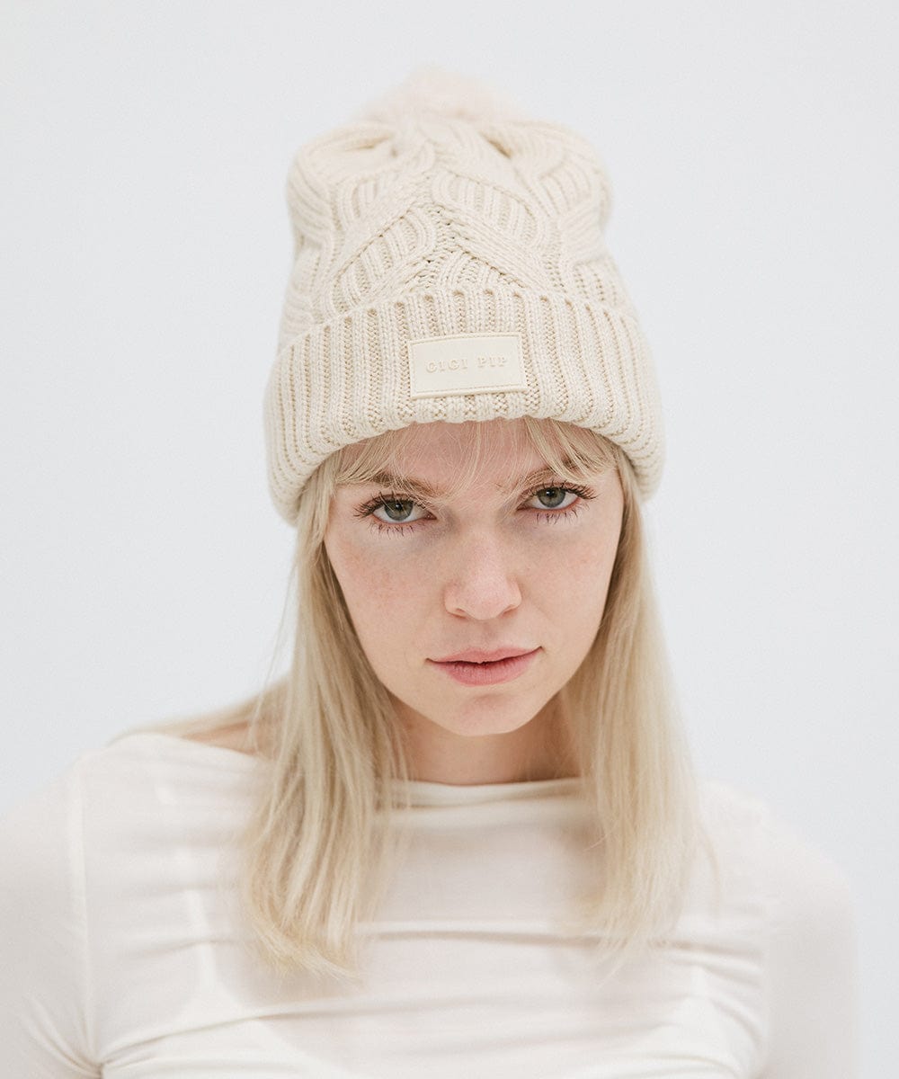 Gigi Pip beanies for women - Ida Cable Knit Beanie - 100% acrylic + faux fur pom beanie featuring Gigi Pip silicone label on foldover brim [cream]