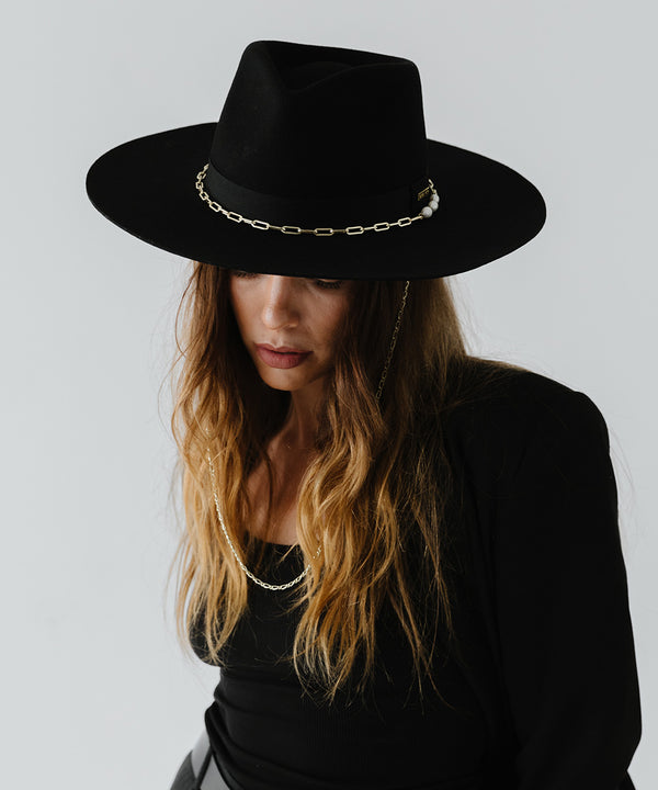 Gigi Pip felt hats for women - Raine Wide Brim Fedora - wide flat brim with a fedora crown, featuring a gold-plated removable paperclip brass chain with three faux pearls and a hand-sewn grosgrain band with the gold Gigi Pip bar around the crown, as well as a removable golden chain chinstrap [black]